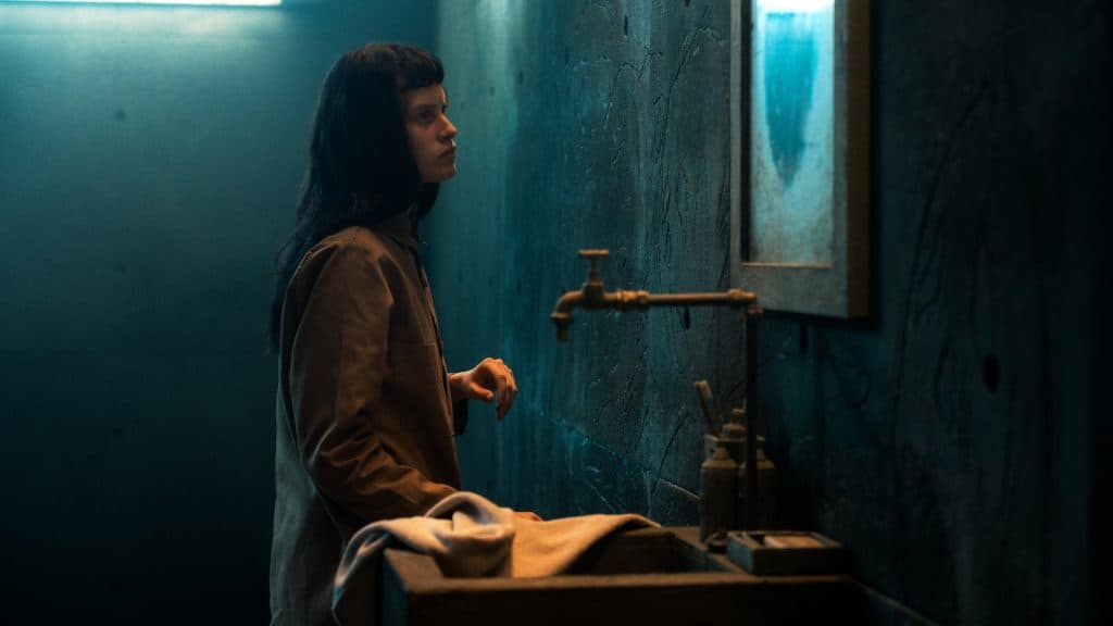 Perempuan en traje marrón en un entorno de concreto mirando en un espejo