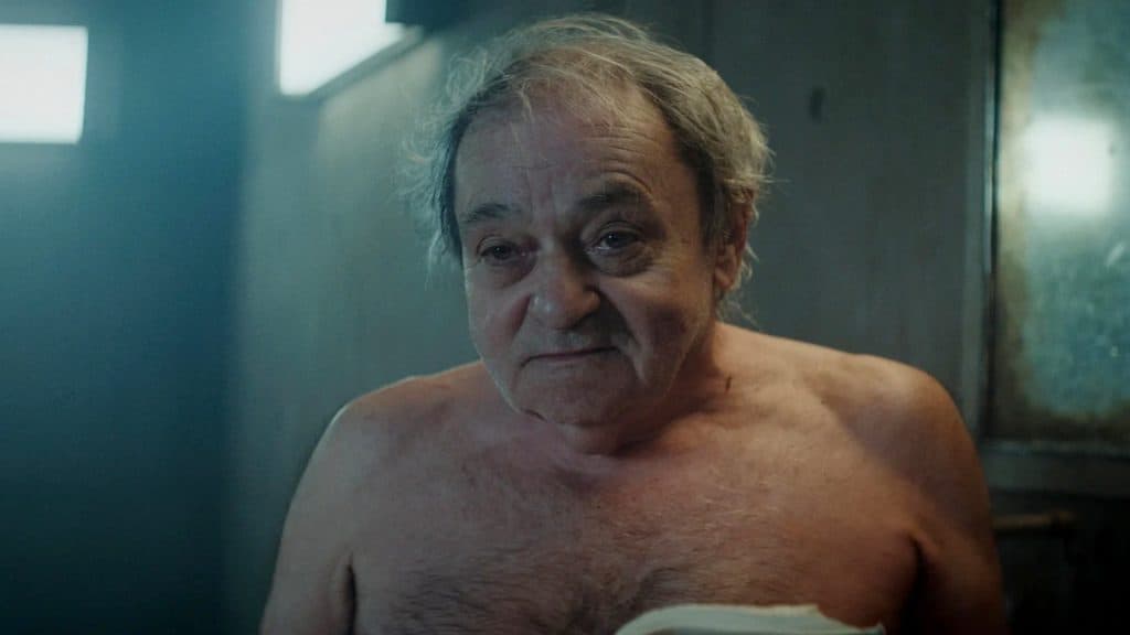 El viejo Trimagasi torso desnudo frente a un espejo en La plataforma