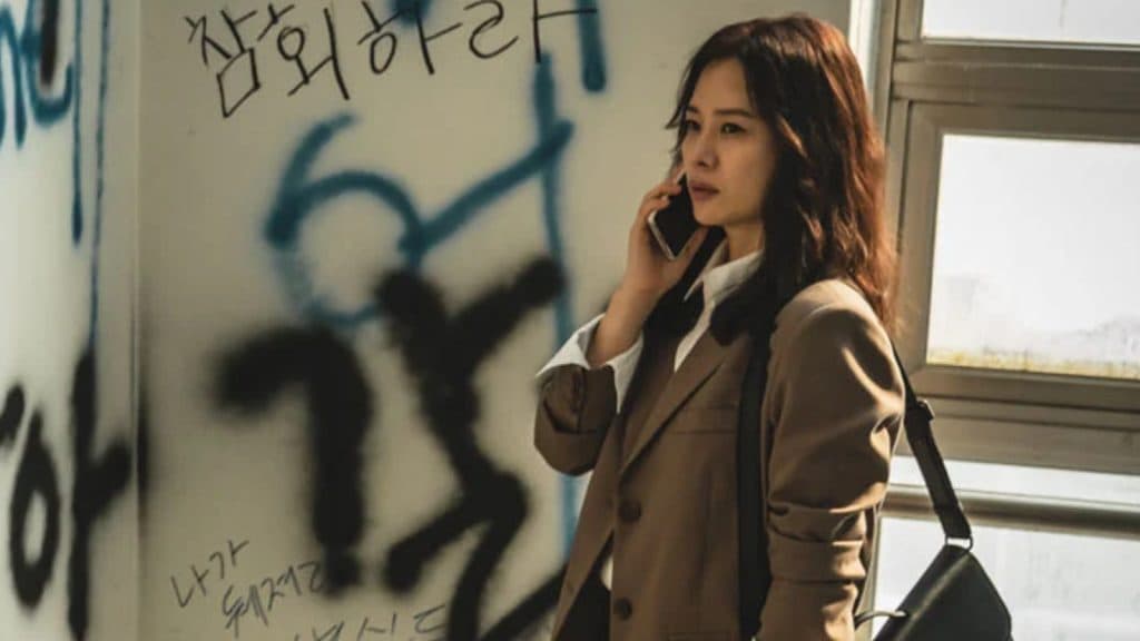 La abogada Min Hyejin hablando por teléfono mira paredes llenas de grafitis en Hellbound