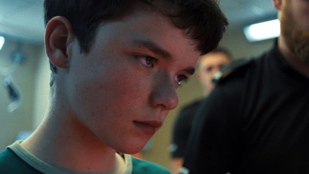 El rostro de Jamie iluminado con la luz roja del escáner de huellas dactilares en Adolescencia